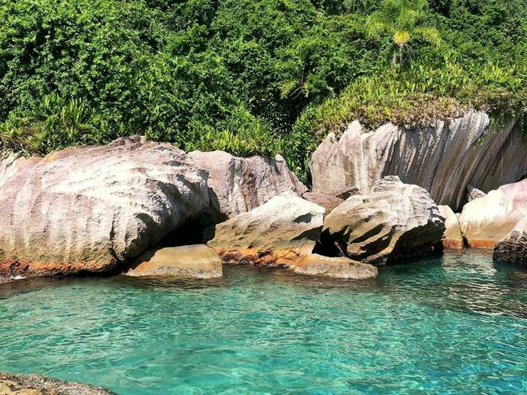 Água cristalina azul-turquesa entre pedras na região de Paraty
